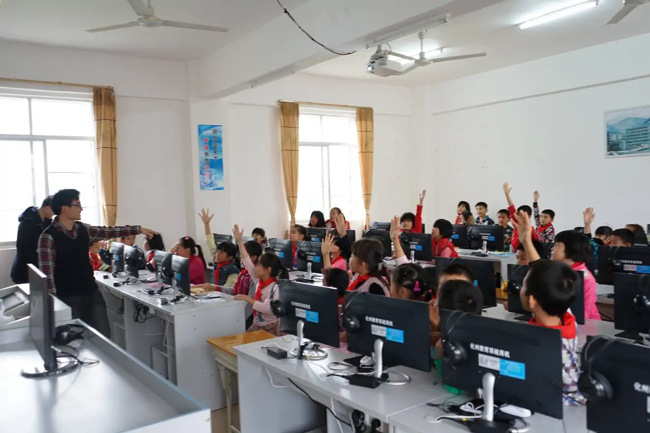 students raising their hands in classroom